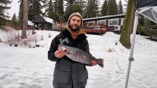 Angler holding a large rainbow trout at a winter fishing derby